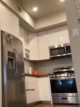 A white kitchen with a stainless refrigerator, microwave, and range