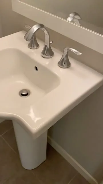 A white pedestal sink with a polished chrome faucet